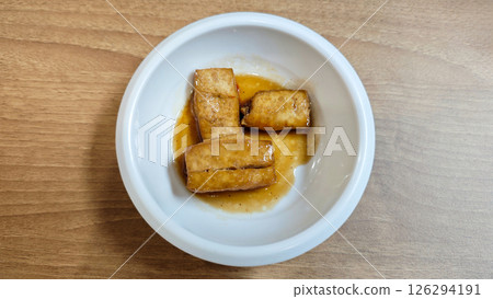 Korean Banchan with Pan-Fried Tofu Served in a White Ceramic Bowl on Wooden Table 126294191