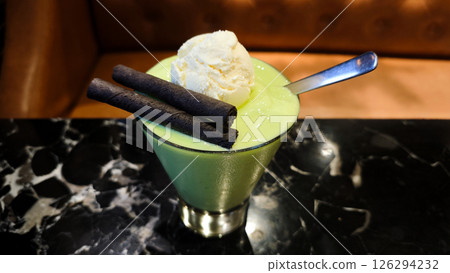 Freshly Blended Avocado Juice with Ice Cream and Chocolate Wafer Sticks Topped in a Clear Glass on a Marble Table Freshly Blended Avocado Juice with Ice Cream and Chocolate Wafer Sticks Topped in a Clear Glass on a Marble Table 126294232