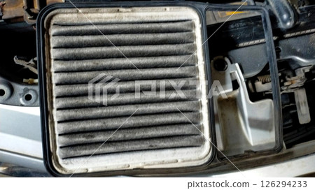 Dirty Car Air Filter Showing Signs of Wear and Accumulation of Dust and Dirt Removed from the Vehicle in a Maintenance Area on a Concrete Surface Dirty Car Air Filter Showing Signs of Wear and Accumulation of Dust and Dirt Removed from the Vehicle in a Maintenance Area on a Concrete Surface 126294233