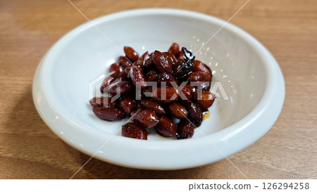 Close-up of Glossy Brown Candied Peanuts in a White Ceramic Bowl on a Light Wooden Table in a Restaurant Setting Close-up of Glossy Brown Candied Peanuts in a White Ceramic Bowl on a Light Wooden Table in a Restaurant Setting 126294258