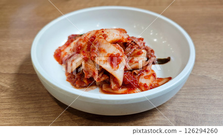 Close-up of Traditional Korean Kimchi in a White Ceramic Bowl on Wooden Table 126294260