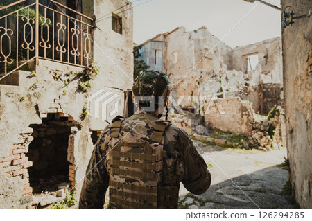 Soldier In Uniform Checks The Walls Of Destroyed Houses In The Village 126294285