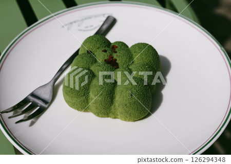 A beautifully presented green dessert sits elegantly on a white plate next to a fork A green-hued dessert rests on a plate under natural light in cafe A beautifully presented green dessert sits elegantly on a white plate next to a fork A green-hued dessert rests on a plate under natural light in cafe 126294348