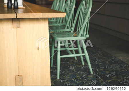 A wooden dining table with green modern chairs creates an inviting and stylish dining space. A detail of a kitchen with a patterned rug on a floor. 126294622