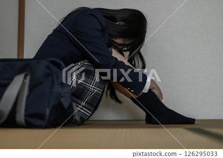 High school girl sitting cross-legged in a Japanese-style room. Bullying, school refusal, social withdrawal, anxiety about the future, no peripheral fading 126295033
