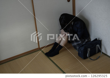 一名高中女生盤腿坐在日式房間的角落。霸凌、拒絕上學、社交退縮、對未來感到焦慮 126295325
