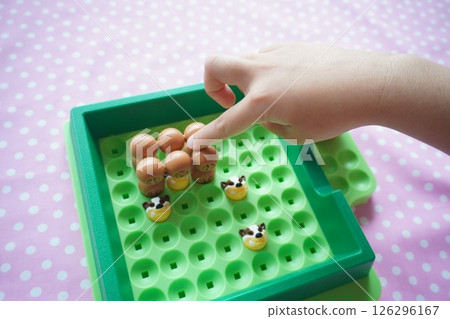 An elementary school-aged child enjoying playing a board game. The child's hand moves the piece. 126296167
