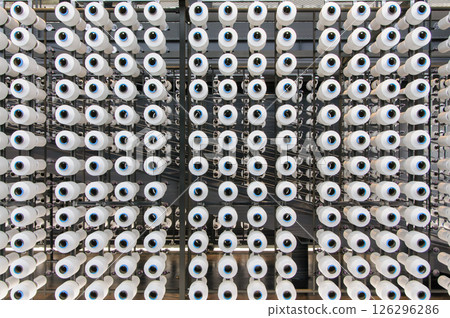 Close-up of industrial textile equipment with lots of yarn creels Close-up of industrial textile equipment with lots of yarn creels 126296286