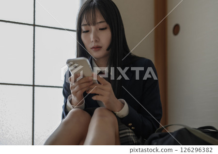 High school girl looking at smartphone in Japanese-style room, bullying, school refusal, SNS trouble 126296382