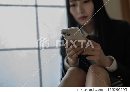 High school girl looking at smartphone in Japanese-style room, bullying, school refusal, SNS trouble 126296395