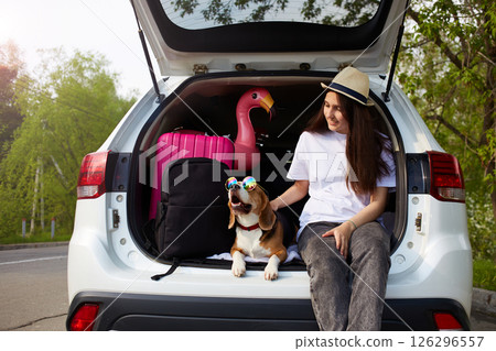 A young girl and a beagle dog are sitting in the trunk of a car. A young girl and a beagle dog are sitting in the trunk of a car. 126296557