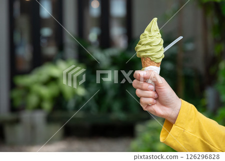 Cropped shot view of someone holding a green tea ice cream. Ice creams are dairy-based frozen foods usually consumed as snacks or desserts. Cropped shot view of someone holding a green tea ice cream. Ice creams are dairy-based frozen foods usually consumed as snacks or desserts. 126296828
