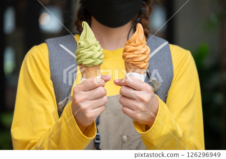 Cropped shot view of woman holding an ice cream. Ice creams are dairy-based frozen foods usually consumed as snacks or desserts. Cropped shot view of woman holding an ice cream. Ice creams are dairy-based frozen foods usually consumed as snacks or desserts. 126296949