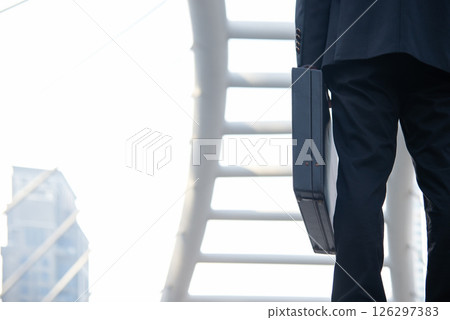 Close up hand holding business bag on the street. Unrecognizable businessman walking Close up hand holding business bag on the street. Unrecognizable businessman walking 126297383