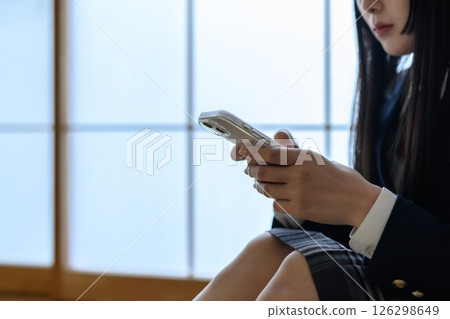 High school girl looking at smartphone in Japanese-style room, bullying, school refusal, SNS trouble, morning color 126298649