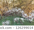 Aerial top down view of ocean waves crashing into rocky shore 126299014