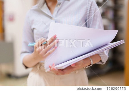 Asian Women Holding Documents for Education Asian Student Reviewing Assignment Academic Paperwork Preparation for Project Studying College Materials and Research 126299553