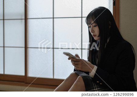 High school girl looking at smartphone in Japanese-style room, bullying, school refusal, SNS trouble High school girl looking at smartphone in Japanese-style room, bullying, school refusal, SNS trouble 126299896