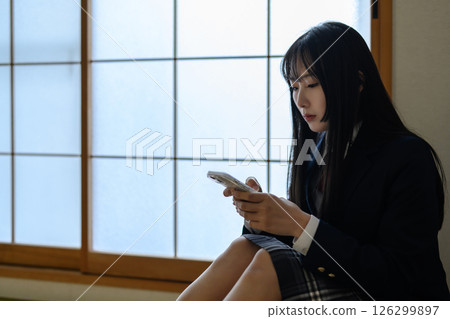 High school girl looking at smartphone in Japanese-style room, bullying, school refusal, SNS trouble, morning color High school girl looking at smartphone in Japanese-style room, bullying, school refusal, SNS trouble, morning color 126299897