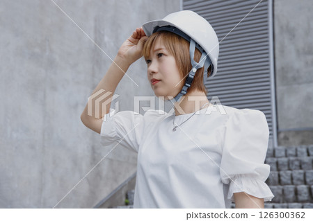 Profile of a woman wearing a helmet and concrete wall background 126300362