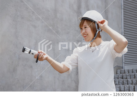 Smiling woman wearing a helmet is holding a flashlight 126300363