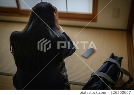 High school girl looking at smartphone placed on tatami in Japanese-style room, bullying, school refusal, SNS trouble, natural color, out of focus person 126300607