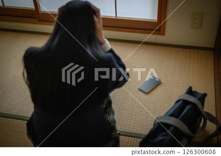高中女生看著日式房間榻榻米上的智慧型手機，霸凌，拒絕上學，SNS 麻煩，自然色 126300608