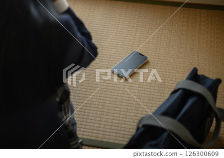 高中女生在日式房間的榻榻米上看著智慧型手機霸凌拒絕上學SNS自然色修剪 126300609