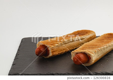Hot dogs served on a dark slate plate for a casual meal Hot dogs served on a dark slate plate for a casual meal 126300816