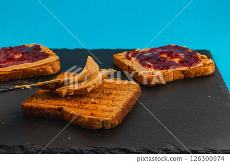 Making peanut butter and jelly toast on a slate board Making peanut butter and jelly toast on a slate board 126300974
