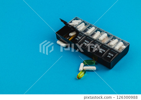 Weekly pill organizer with various capsules on a blue background Weekly pill organizer with various capsules on a blue background 126300988