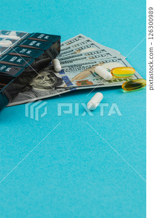 Money and medications arranged on a blue background Money and medications arranged on a blue background 126300989