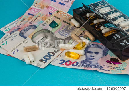 Currency and medication displayed on a blue background Currency and medication displayed on a blue background 126300997