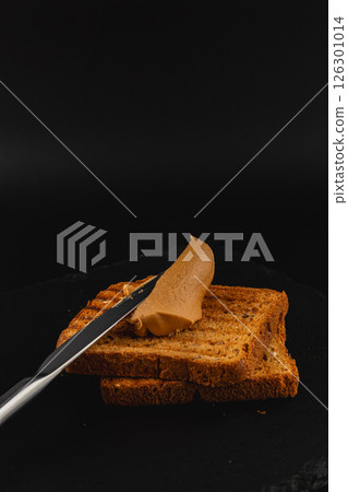 Slicing smooth spread onto fresh toasted bread 126301014