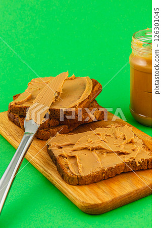 Slices of bread topped with creamy peanut butter on wood Slices of bread topped with creamy peanut butter on wood 126301045