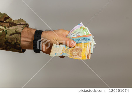 Hand holding assorted banknotes against a plain background Hand holding assorted banknotes against a plain background 126301074