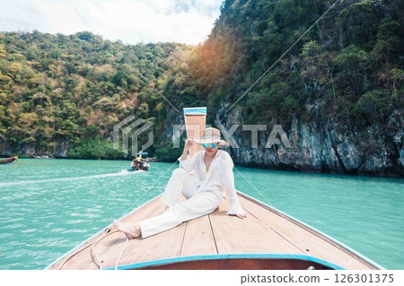 Happy Woman tourist in private longtail boat trip to koh Hong lagoon island at Krabi, Thailand. landmark, tropical destination, southeast Asia Travel, summer vacation, wanderlust and holiday concept 126301375