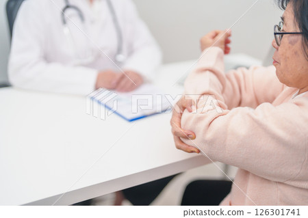 Elderly Woman having elbow ache and consulting doctor in hospital. muscle pain due to lateral epicondylitis or tennis elbow. injury, Health and medical consultation concept Elderly Woman having elbow ache and consulting doctor in hospital. muscle pain due to lateral epicondylitis or tennis elbow. injury, Health and medical consultation concept 126301741