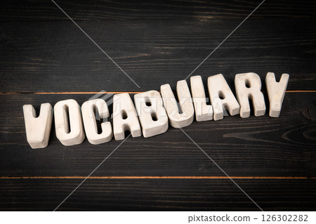 Vocabulary. Concrete alphabet letters on a black wooden texture background Vocabulary. Concrete alphabet letters on a black wooden texture background 126302282