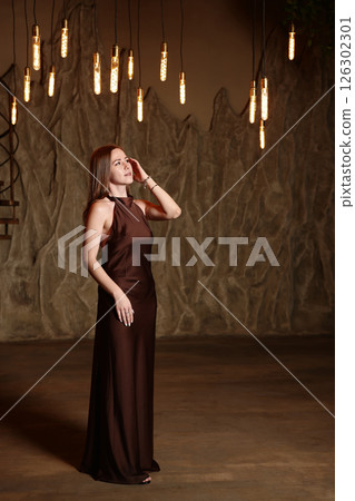 An Elegant Woman Dressed in a Beautiful Brown Dress Surrounded by Soft Ambient Lighting 126302301