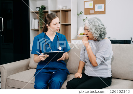 Young nurse helping elderly woman walk in the room, holding his hand, supporting. Treatment and rehabilitation after injury in assisted living facility Young nurse helping elderly woman walk in the room, holding his hand, supporting. Treatment and rehabilitation after injury in assisted living facility 126302343
