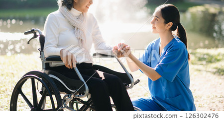 Elderly asian senior woman on wheelchair with Asian careful caregiver and encourage patient, walking in garden. with care from a caregiver. and senior health insurance 126302476