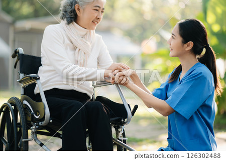 Elderly asian senior woman on wheelchair with Asian careful caregiver and encourage patient, walking in garden. with care from a caregiver. and senior health insurance 126302488