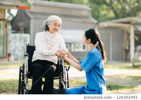 Elderly asian senior woman on wheelchair with Asian careful caregiver and encourage patient, walking in garden. with care from a caregiver. and senior health insurance 126302491