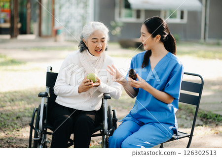 Elderly asian senior woman on wheelchair with Asian careful caregiver and encourage patient, walking in garden. with care from a caregiver. and senior health insurance 126302513