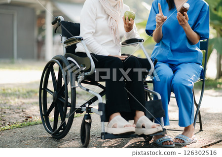 Elderly asian senior woman on wheelchair with Asian careful caregiver and encourage patient, walking in garden. with care from a caregiver. and senior health insurance 126302516