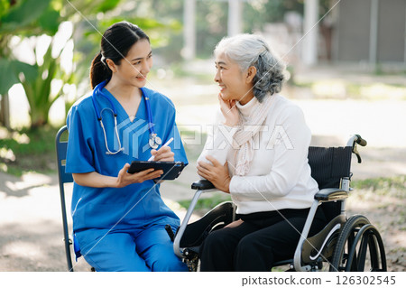 Elderly asian senior man on wheelchair with Asian careful caregiver. Nursing home hospital garden concept are walking in the garden. 126302545
