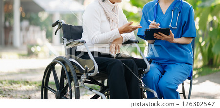 Elderly asian senior man on wheelchair with Asian careful caregiver. Nursing home hospital garden concept are walking in the garden. Elderly asian senior man on wheelchair with Asian careful caregiver. Nursing home hospital garden concept are walking in the garden. 126302547