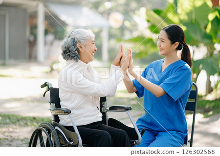 Elderly asian senior woman on wheelchair with Asian careful caregiver and encourage patient, walking in garden. with care from a caregiver 126302568