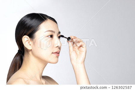Profile of a beautiful Japanese woman applying mascara - AI-generated image 126302587